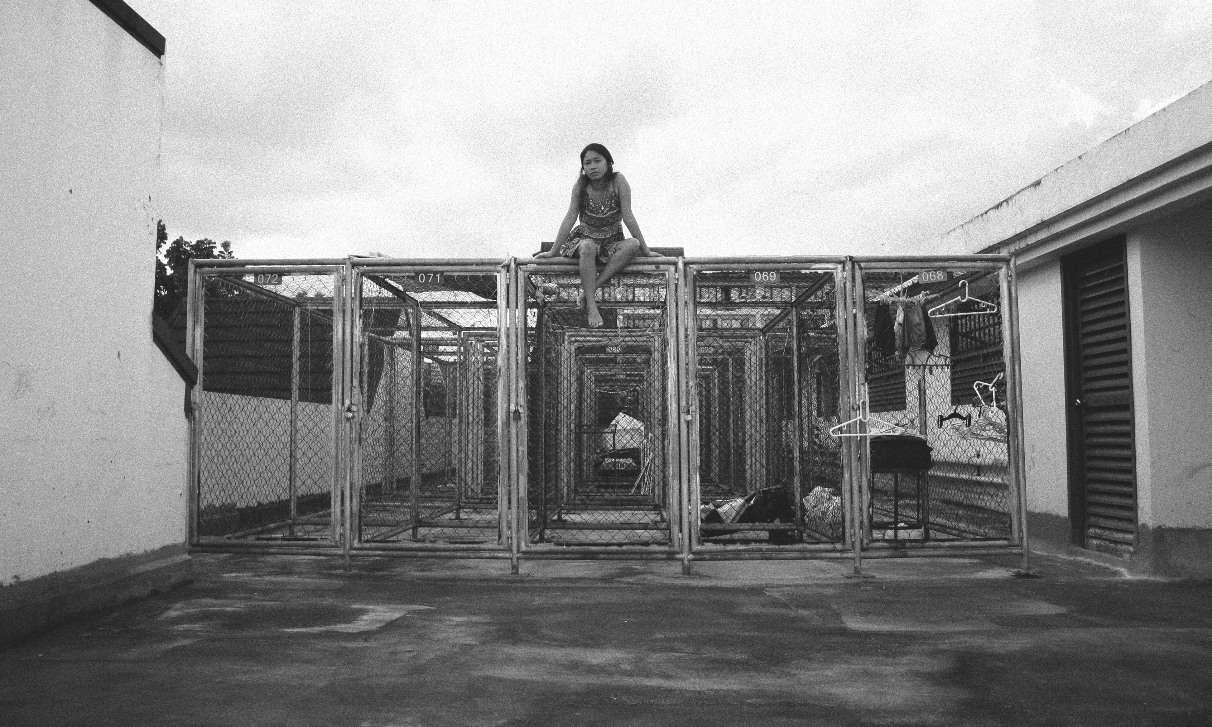 grayscale photo of woman sitting on top of cage